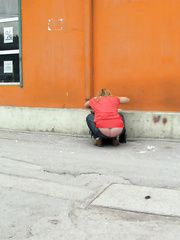 Young lady with beautiful panty less bum searching for something in her bag on the street