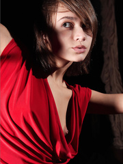 Sultry erotic model in red lengthy suit posing seductively with miniature scones bared