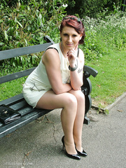 Thick woman in glasses shows off her stiletto heels on a park bench