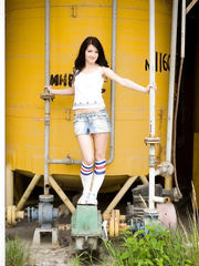 Small Russian gal Lina seductively positions outdoors near large yellow reservoir