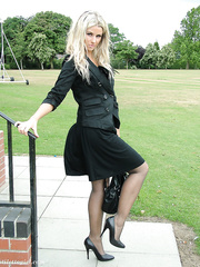 Erotic model in darksome costume flaunts her lengthy legs in sheer hose outside