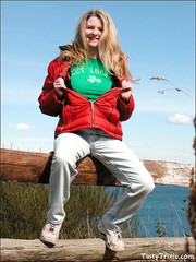 Older woman slips jeans and pants over her gazoo by a wooden post fence