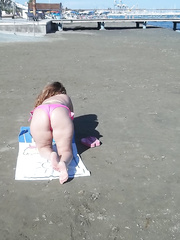 Milf wife resting on the beach in bright pink and yellow bikini