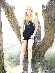 Sexy legal age teenager model Whitney undresses in nature's garb up against a tree in the park