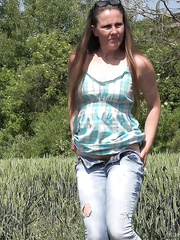 Mature brunette hair NicolD whips down her blue jeans to urinate in the tall grass