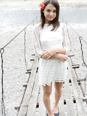 Diminutive legal age teenager wears a flower in her hair during the time that posing in nature's garb on suspension bridge