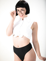 Black haired sweetheart Olive Glass removes glasses previous to standing undressed