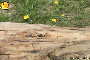 Lovely brunette hair babe urinates behind the green hedge