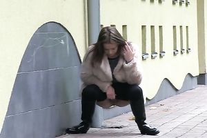 Brunette in fur jacket and dark pants plan to pee right outdoors