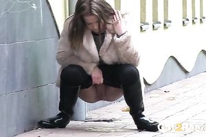 Brunette in fur jacket and dark pants plan to pee right outdoors