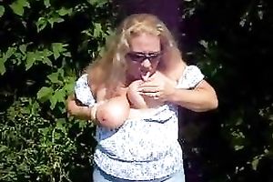 Cougar golden-haired lady in sunglasses flashing her wobblers outside
