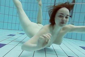 Curvy pale skin redhead chick in the water swims undressed