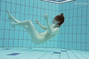 Curvy pale skin redhead chick in the water swims undressed