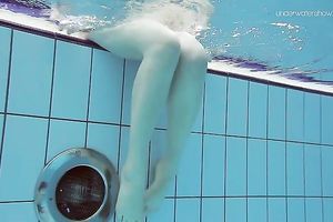 Curvy pale skin redhead chick in the water swims undressed