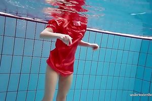 Slender and cute redhead white wife dives in the pool and disrobes underwater