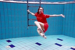 Slender and cute redhead white wife dives in the pool and disrobes underwater