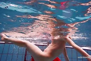 Slender and cute redhead white wife dives in the pool and disrobes underwater