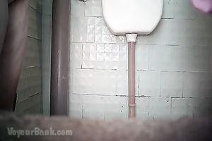 Chunky aged white woman in the biffy room filmed from front