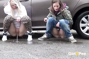 Two European dilettante skanks pissing behind the car
