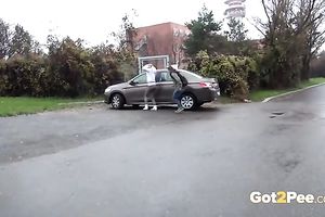 Two European dilettante skanks pissing behind the car