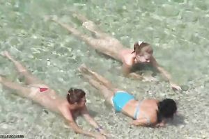 Spying on charming MILFs bathing in the ocean at the naked beach