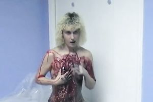 Curly-haired non-professional golden-haired smears her body with paint indoors