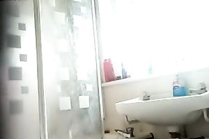 Slim dark brown beauty with tanned skin washes her body in shower