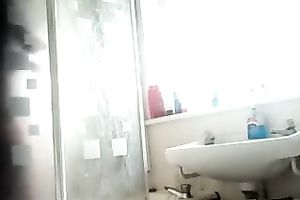 Slim dark brown beauty with tanned skin washes her body in shower