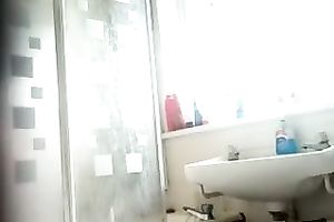 Slim dark brown beauty with tanned skin washes her body in shower