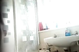 Slim dark brown beauty with tanned skin washes her body in shower