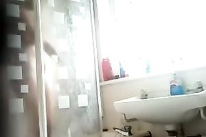 Slim dark brown beauty with tanned skin washes her body in shower