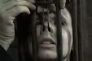 Brunette sweetheart wearing head cage receives her snatch and face hole screwed with a fake penis