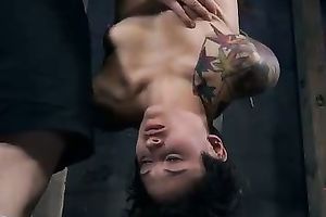Salacious nympho with tattoos is hanging upside down in the dungeon
