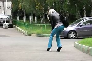 Skinny Russian golden-haired girl walks on the sidewalk and pisses