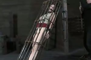 Redhead honey with steel mask on her head is captured in a cage