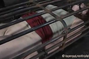 Redhead honey with steel mask on her head is captured in a cage