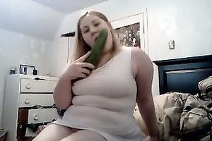 Delightful golden-haired honey with a large cucumber tries to eat it