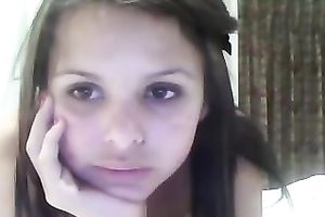 Brunette legal age teenager with big fake mounds fingers her twat in front of a web camera