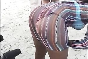 Lewd swarthy playgirl flashes her wazoo and slit on a beach