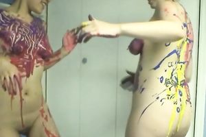 Two cute women smear each other's bodies with paints